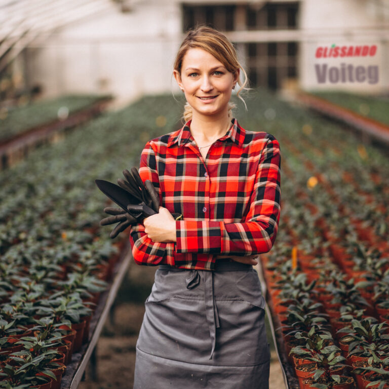 Woman gardner looking after plants in a greenhouse
